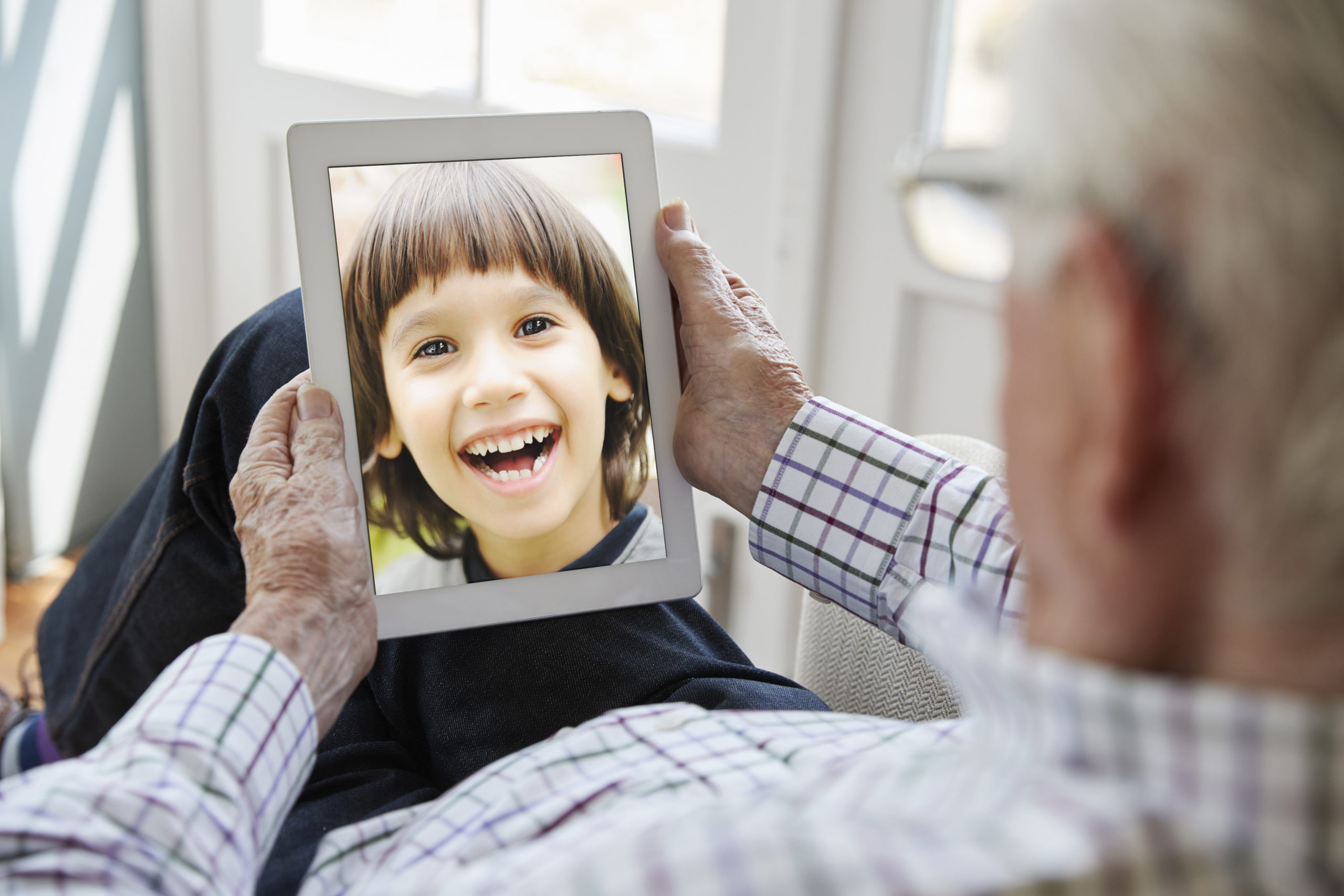 Senior Media Care - Senior telefoniert per Video mit seinem Enkel